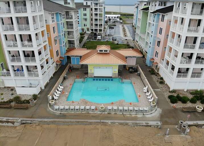 Aerial View Of Pale Buildings Surrounding A Pool By The Beach
