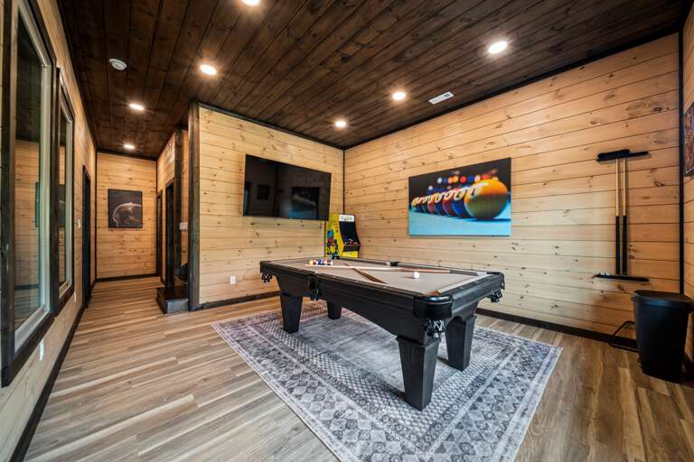 Game room with pool table, arcade machines, and pool view