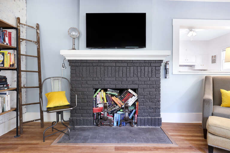 Living Room With Books In Fireplace And TV Above