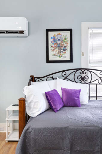Interior Of A Bedroom With Gray Bedding And Purple Pillows