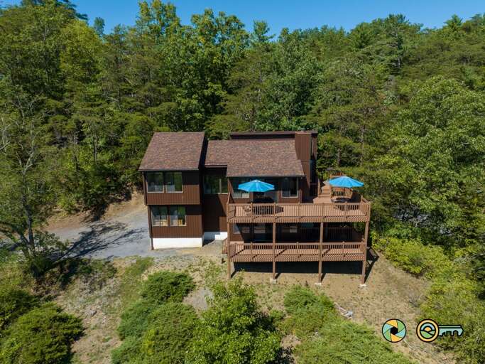 Aerial View Of A Two-story Building With A Deck Surrounded By Trees Aerial View Of A Two-story Building With A Deck Surrounded By Trees