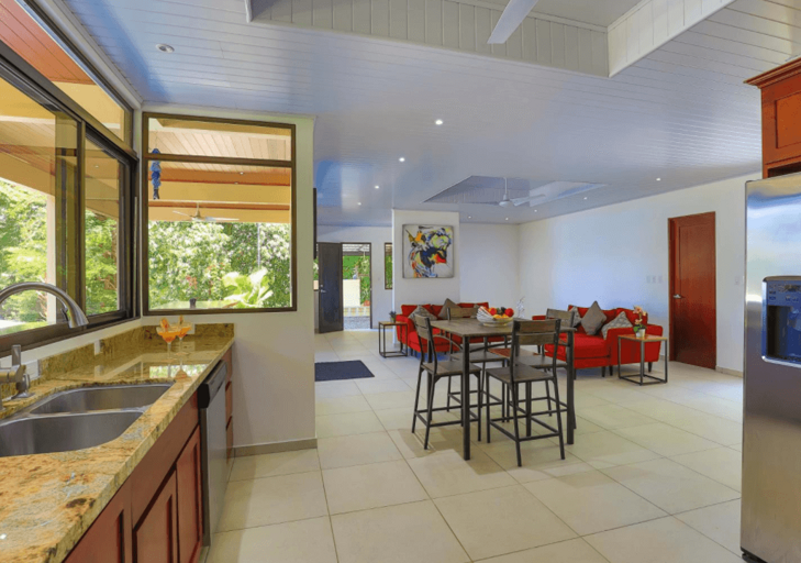 Modern Kitchen With Bar Counter Opening To A Living Area With Red Chairs