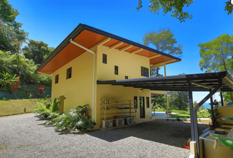 Two-story Yellow Building With Carport And Tropical Vegetation