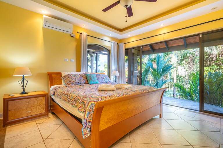 Sunlit Room With Vibrant Bedspread, Tropical Garden View Through Glass Doors
