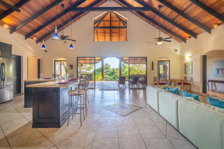 Spacious Interior With High Ceilings And Hardwood Beams, Leading To A Breezy Balcony View