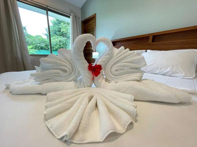 Swan-shaped Towels On A Bed With A Flower Swan-shaped Towels On A Bed With A Flower
