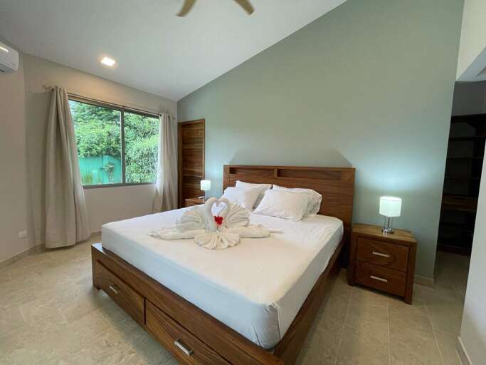 Modern Bedroom With Large Bed, Nightstand, And View Of Greenery Through Window Modern Bedroom With Large Bed, Nightstand, And View Of Greenery Through Window