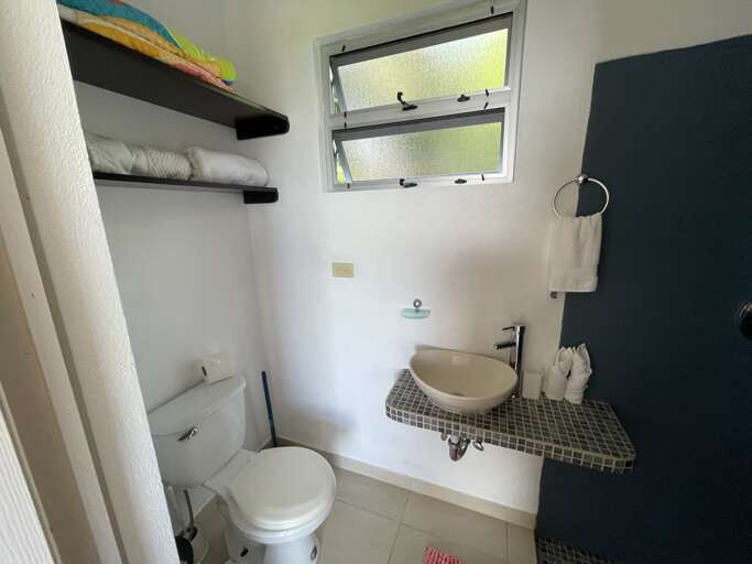 Small Bathroom With White Toilet, Sink, And Towels On Shelf Small Bathroom With White Toilet, Sink, And Towels On Shelf