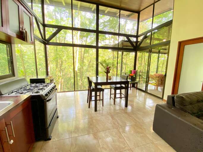 Interior View Of A Room With Large Windows, Kitchen Area, Dining Table, And Sofa Interior View Of A Room With Large Windows, Kitchen Area, Dining Table, And Sofa