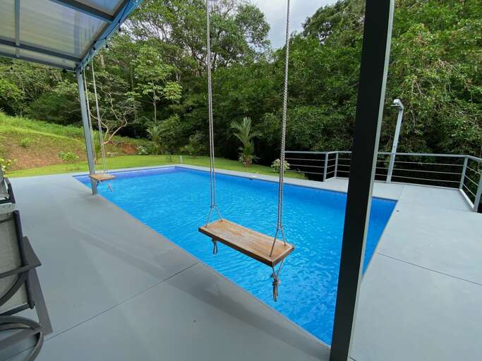 Swing Over Outdoor Swimming Pool With Surrounding Greenery