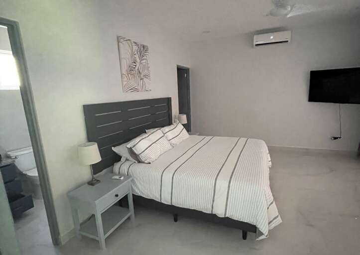 Minimalist Style Bedroom With A Striped Bedspread And Wall-mounted TV