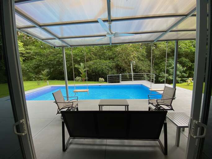 Patio View Of A Swimming Pool With Chairs And Greenery