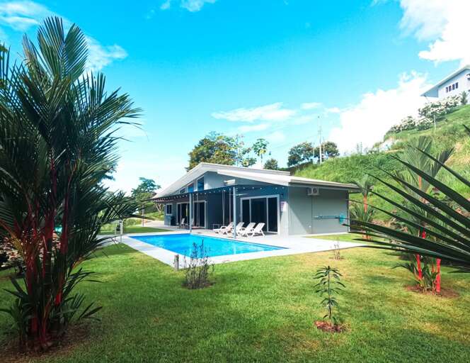 Blue Bungalow Beside Bright Pool, Surrounded By Lush Greenery