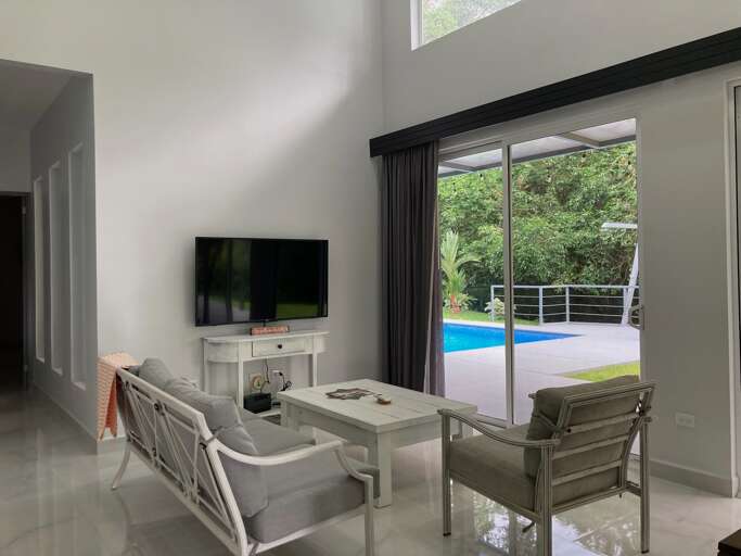 Living Room With Television And Sliding Door Opening To A Pool