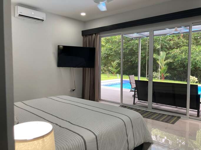 Modern Room With Bed, TV And Sliding Doors To Pool Area