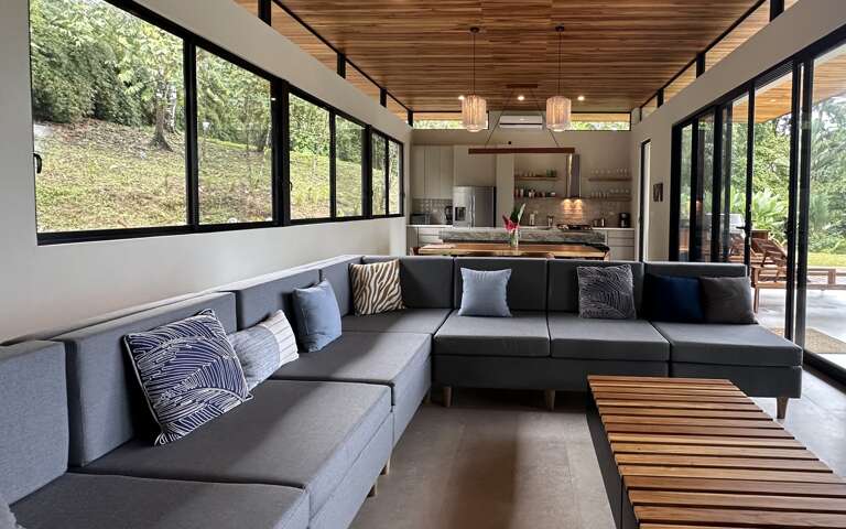 Modern Living Room Interior With Large Windows And Kitchen In Background Modern Living Room Interior With Large Windows And Kitchen In Background