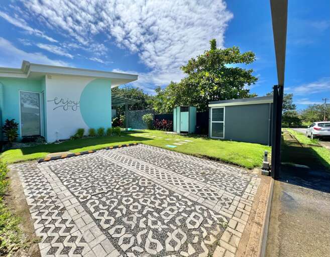 Suburban House With Patterned Driveway And Lawn Under Blue Sky