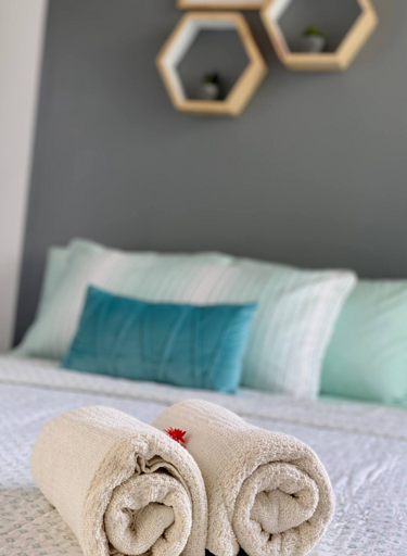 Modern Bedroom Interior With Rolled Towels On Bed And Hexagonal Wall Shelves