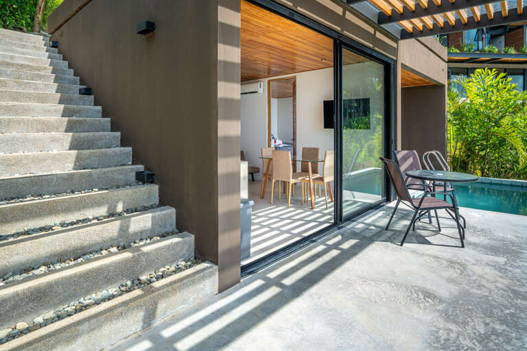 Modern Outdoor Seating Area Next To Open Sliding Glass Doors And Stairs