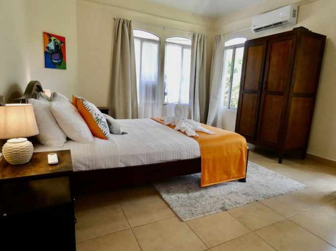 Interior Of A Bedroom With A Large Bed, Bedside Lamp, Wardrobe, And Curtains