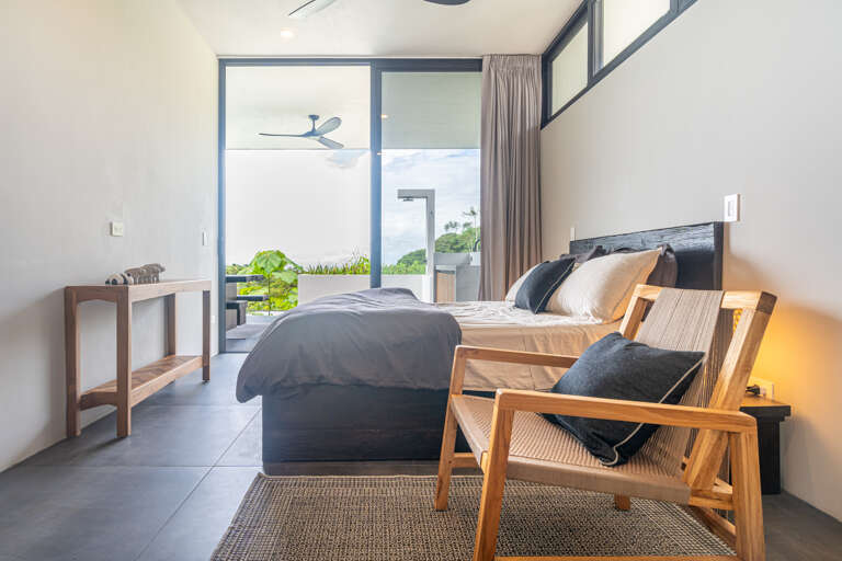 A beautifully appointed bedroom with large windows, providing serene views of both the pool and the lush greenery outside. A beautifully appointed bedroom with large windows, providing serene views of both the pool and the lush greenery outside.