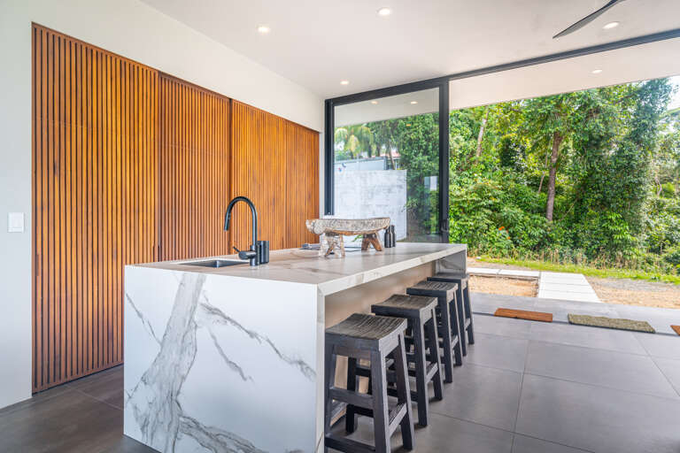 An expansive kitchen with a distinctive layout, offering stunning views of the natural landscape and the pool, creating a perfect balance of indoor and outdoor living. An expansive kitchen with a distinctive layout, offering stunning views of the natural landscape and the pool, creating a perfect balance of indoor and outdoor living.