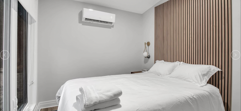 Modern Bedroom With White Bedding And Wooden Wall Accent