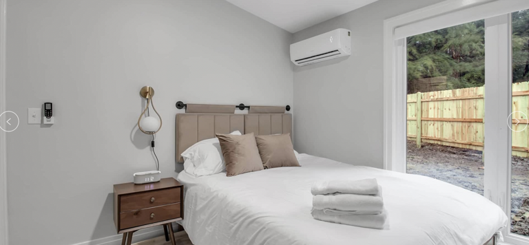 Modern Bedroom With White Bedding And Sliding Door Access To Outside