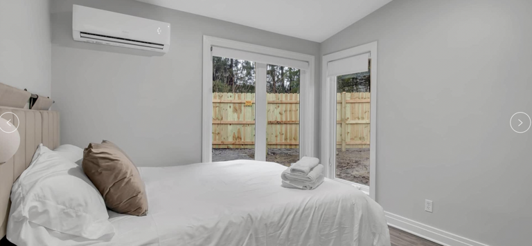 Modern Bedroom With Large Bed And French Doors Leading To A Fence