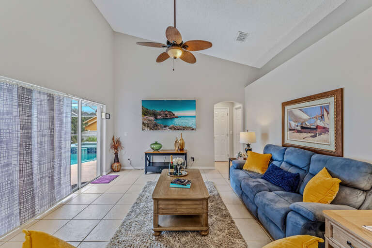 Interior Of A Living Room With Blue Sofa, Paintings, And Pool View Interior Of A Living Room With Blue Sofa, Paintings, And Pool View