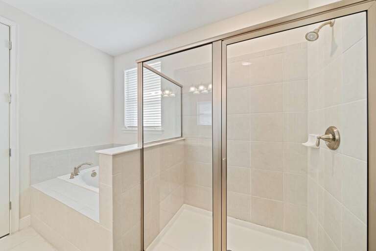 Bathroom with dual sinks, jetted tub, and glass enclosed shower