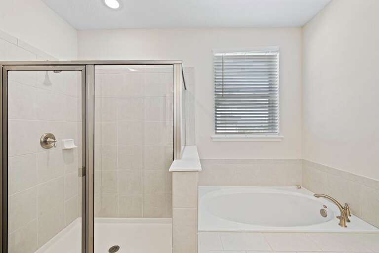 Bathroom with dual sinks, jetted tub, and glass enclosed shower