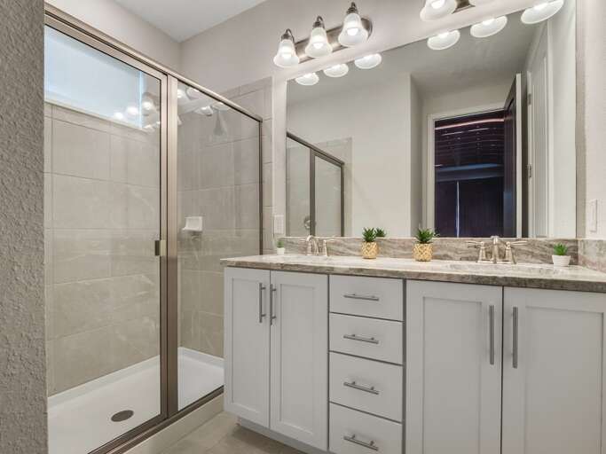Bathroom with dual sinks and glass enclosed shower