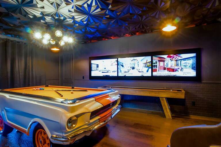 Secret agent themed game room with Mustang pool table, shuffleboard, flat screen TVs, and massage chairs