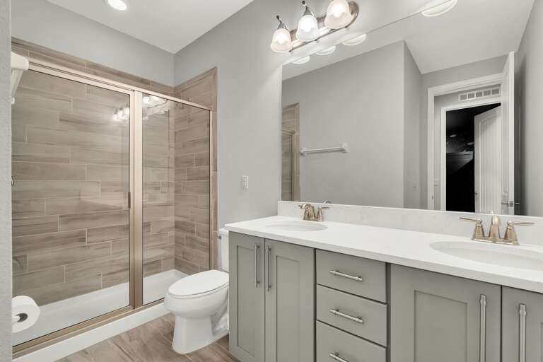 Bathroom with dual sinks and glass enclosed shower