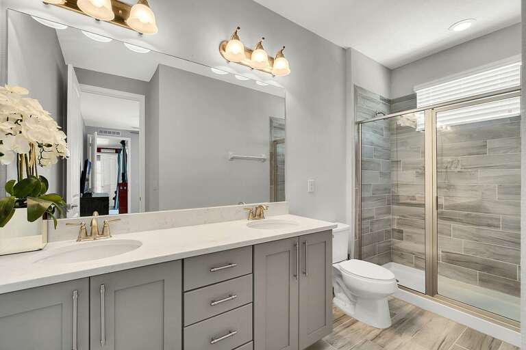 Bathroom with dual sinks and glass enclosed shower