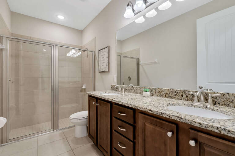 Bathroom with dual sinks and glass enclosed shower
