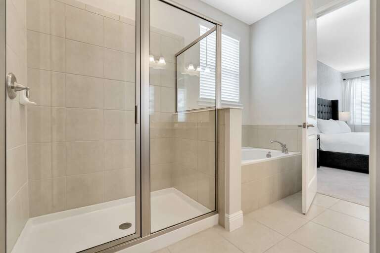 Bathroom with dual sinks, glass enclosed shower, and a large soaker tub