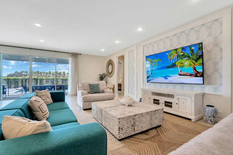 Living area with contemporary furniture, flat screen TV, and sliding doors to lanai and pool area