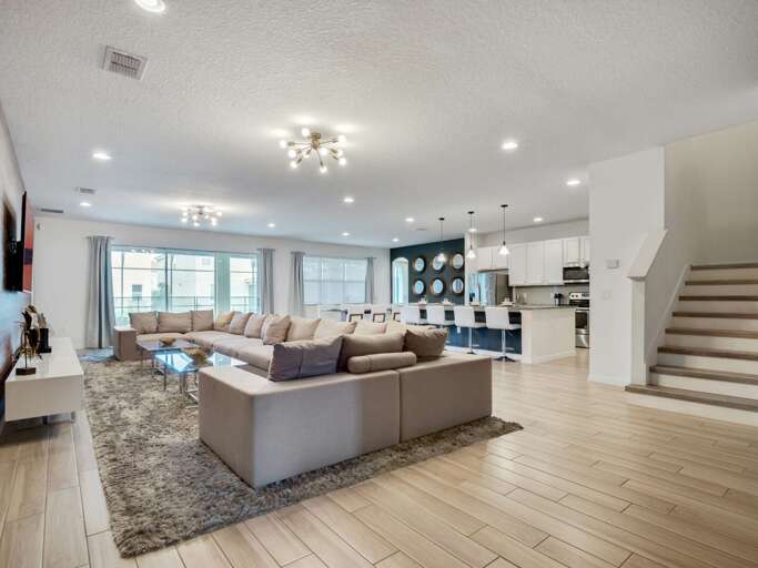 Living area with comfy sectional sofa, flat screen TV, and sliding doors to lanai and pool area