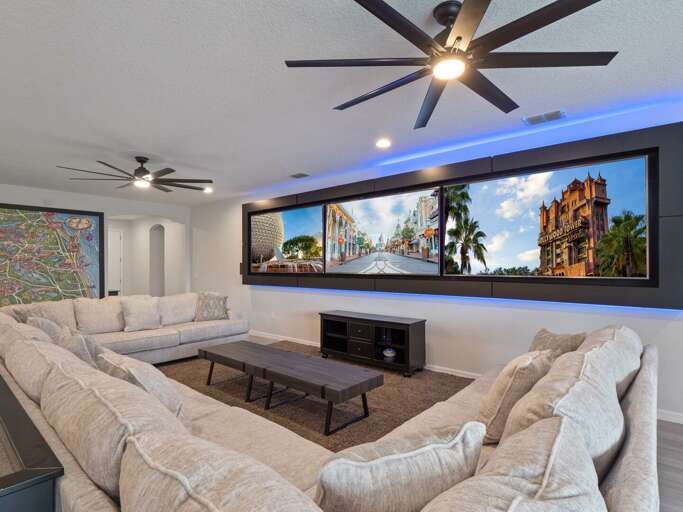 Living area with huge U-shaped sectional sofa and three large framed 86” TV