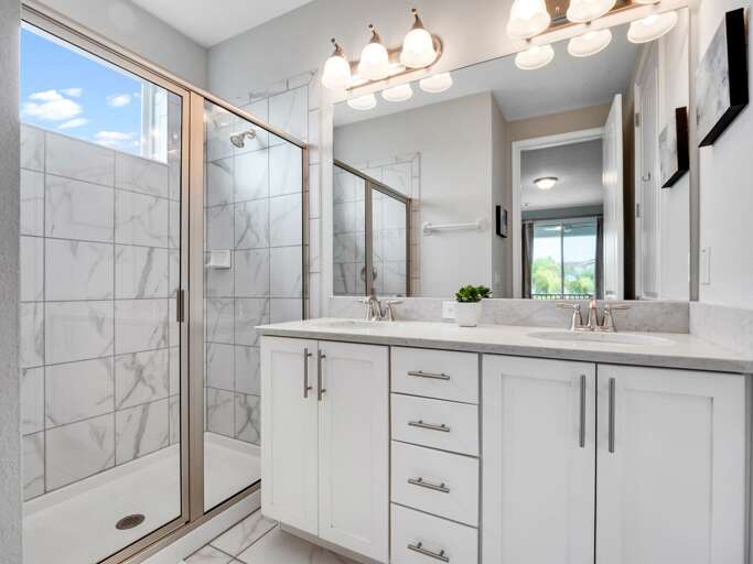 Bathroom with dual sinks and glass enclosed shower