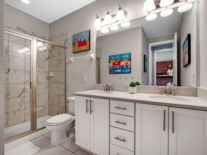 Bathroom with dual sinks and glass enclosed shower