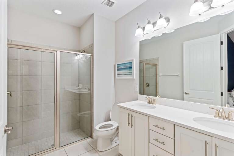 Bathroom with dual sinks and glass enclosed shower