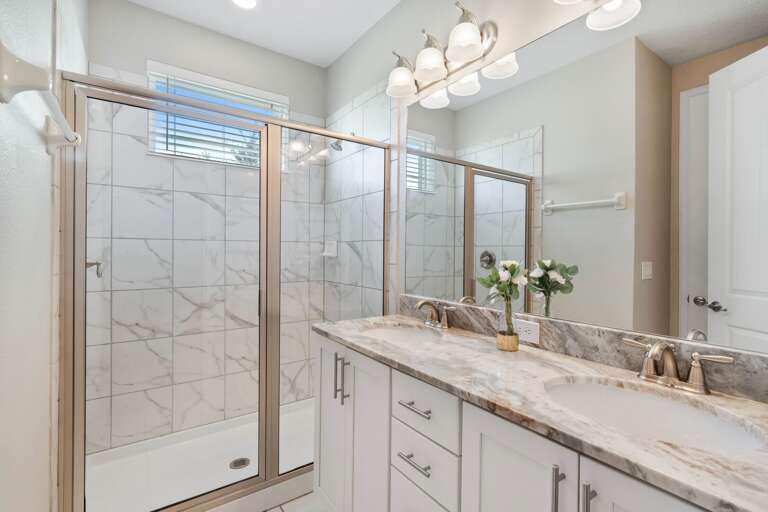 Bathroom with dual sinks and glass enclosed shower