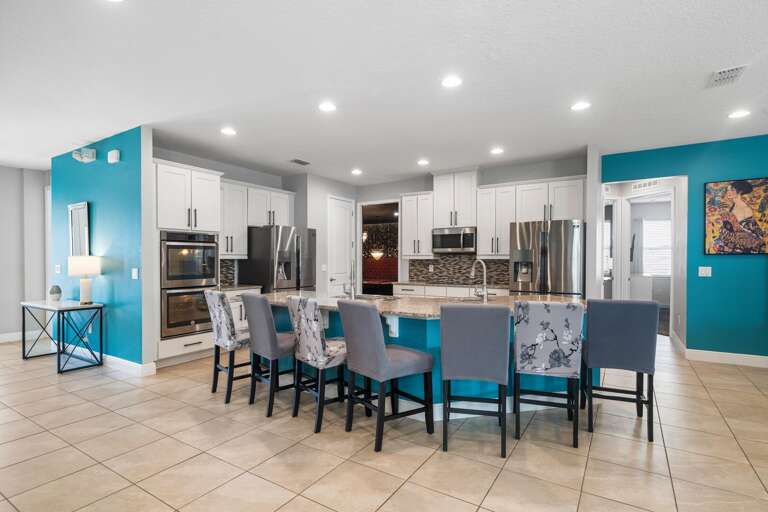 - Bright kitchen with large dining table.
- Modern kitchen island with seating.
- Spacious open kitchen and dining area.