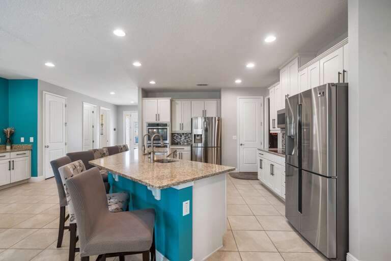 - Bright kitchen with large dining table.
- Modern kitchen island with seating.
- Spacious open kitchen and dining area.