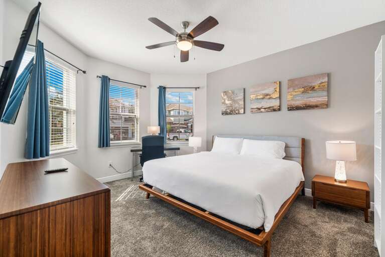 -A large bed with crisp white bedding
- Warm wood furniture
- Bright, calm, and ready to unwind