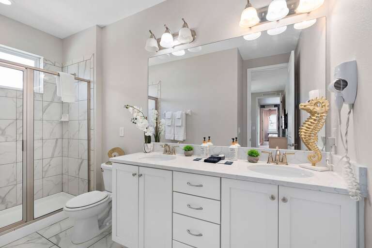 Bathroom w/ dual sinks and glass enclosed shower
