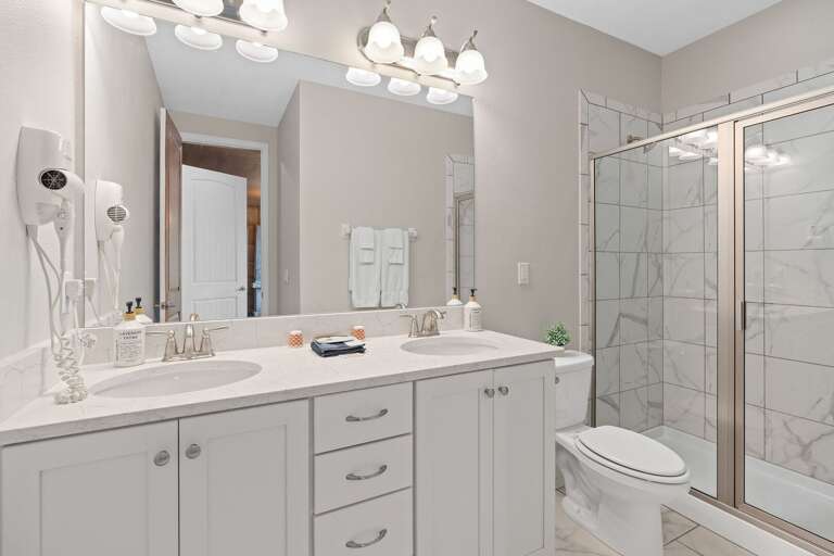 Bathroom w/ dual sinks and glass enclosed shower
